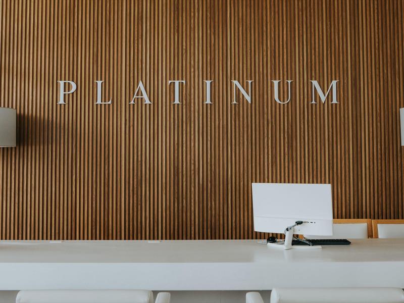 Reception desk with wooden panel and "PLATINUM" sign on the wall.