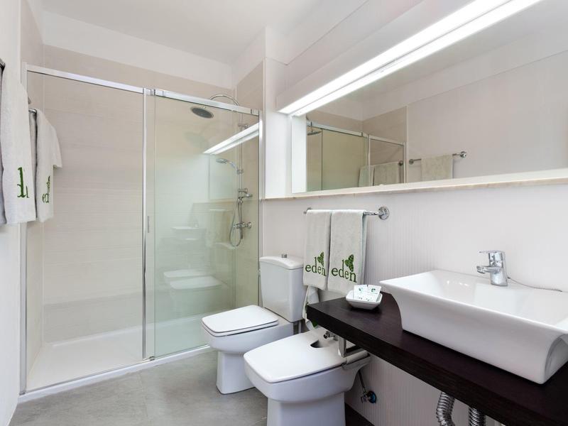 Modern bathroom with shower, toilet, bidet, sink, and large mirror.