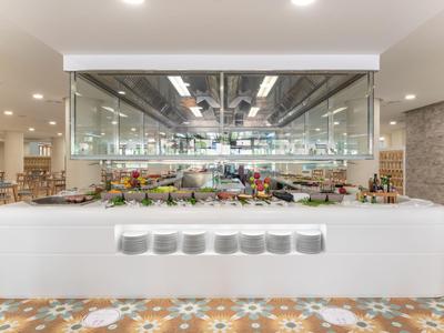 Buffet moderne avec comptoir blanc et grande vitrine en verre dans une salle à manger lumineuse.