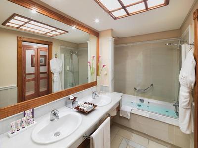 Salle de bain moderne avec deux lavabos, grand miroir et baignoire.