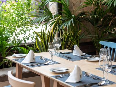 Table à manger élégamment dressée avec des verres à vin et des serviettes blanches dans un cadre tropical.