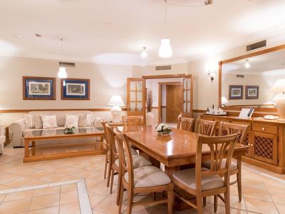 Salle à manger lumineuse avec table et chaises en bois, canapé et grands miroirs aux murs.