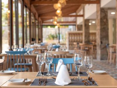 Restaurant élégant avec des tables dressées et de grandes fenêtres donnant sur un jardin.