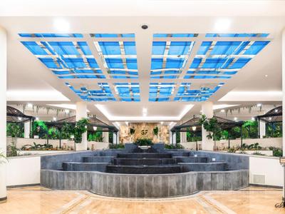 Grand hall d'hôtel avec fontaine centrale et plafond décoratif à motif bleu.