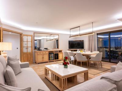 Salon et salle à manger modernes avec grandes fenêtres et mobilier élégant aux tons chaleureux.