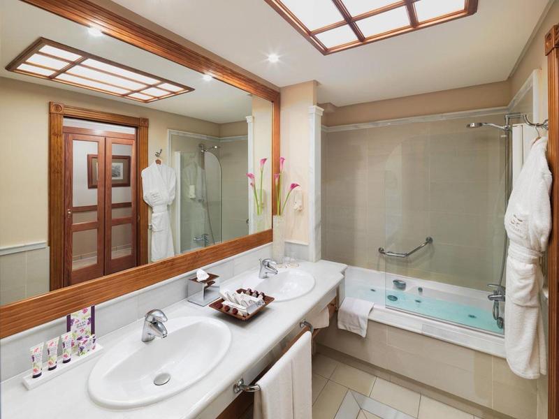 Salle de bain moderne avec deux lavabos, grand miroir et baignoire.