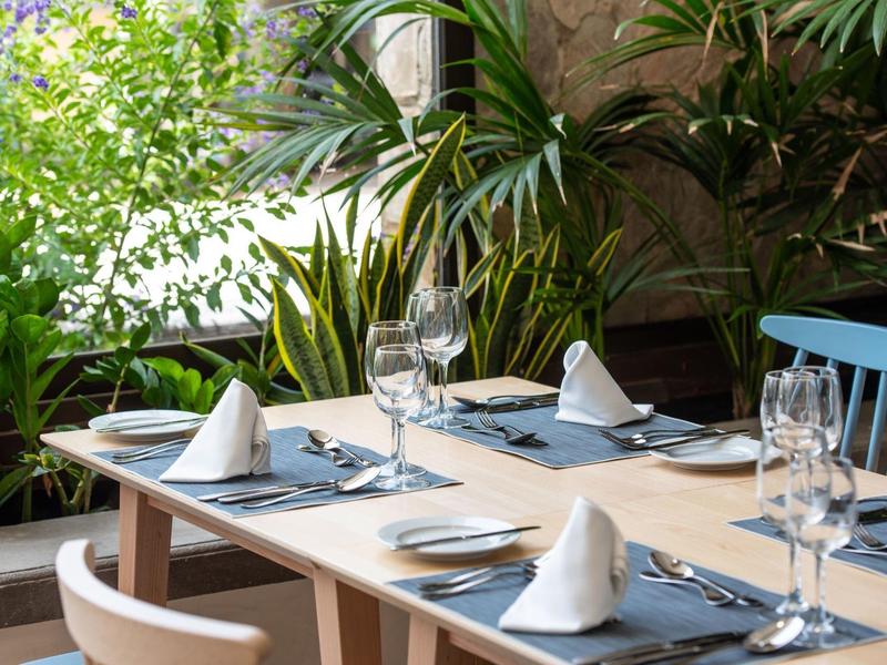 Table à manger élégamment dressée avec des verres à vin et des serviettes blanches dans un cadre tropical.
