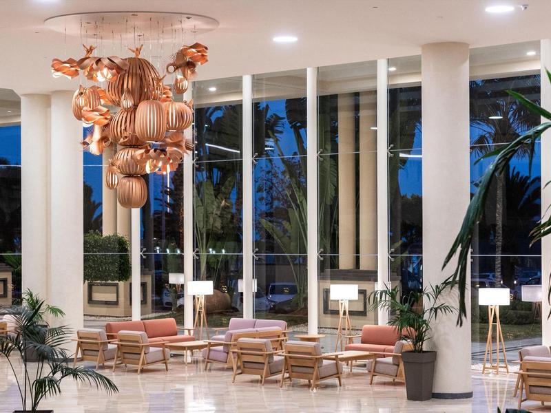 Hall d'hôtel lumineux avec luminaires en cuivre modernes et sièges confortables.