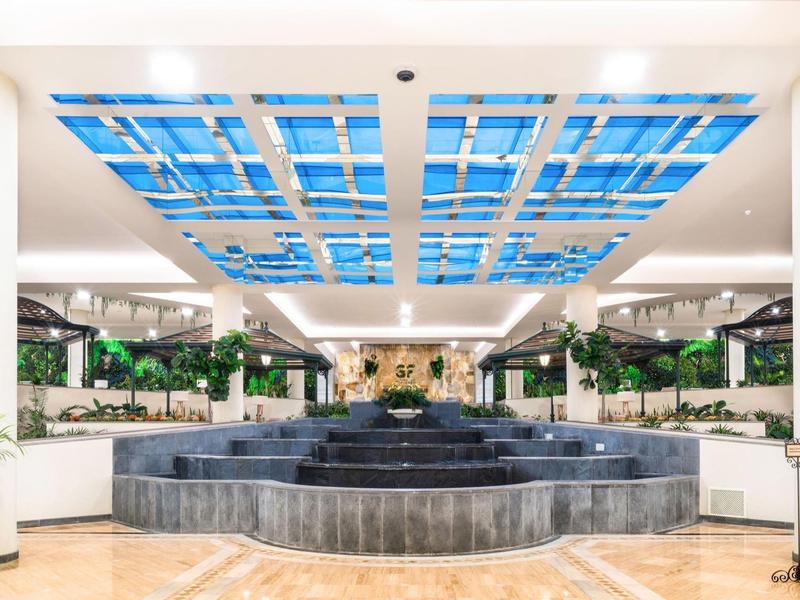 Grand hall d'hôtel avec fontaine centrale et plafond décoratif à motif bleu.