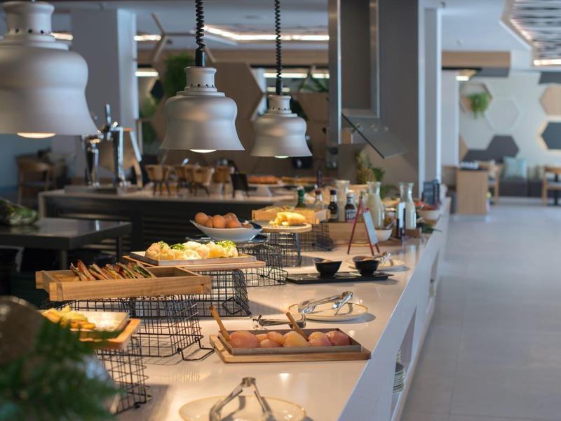 Modern buffet table with various pastries and breads in a bright dining area.