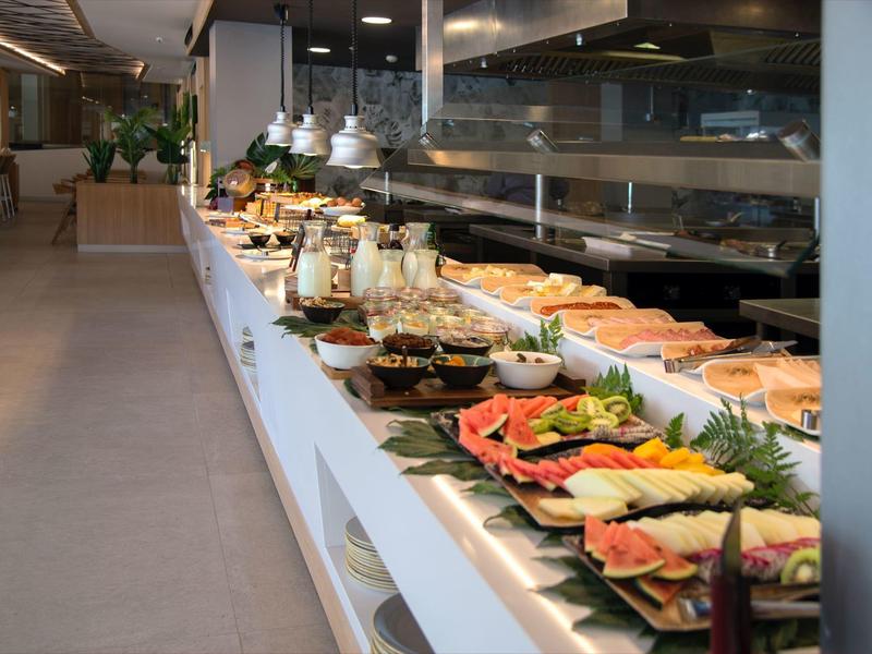 Buffet spread with various fruits, breads, and breakfast items in a modern dining area.