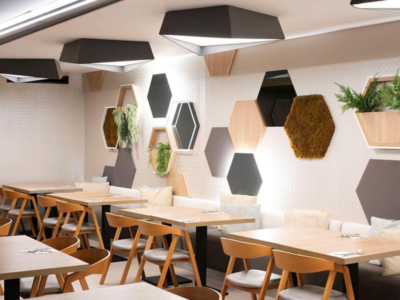 Modern dining area with hexagonal wall decor and wooden tables and chairs.
