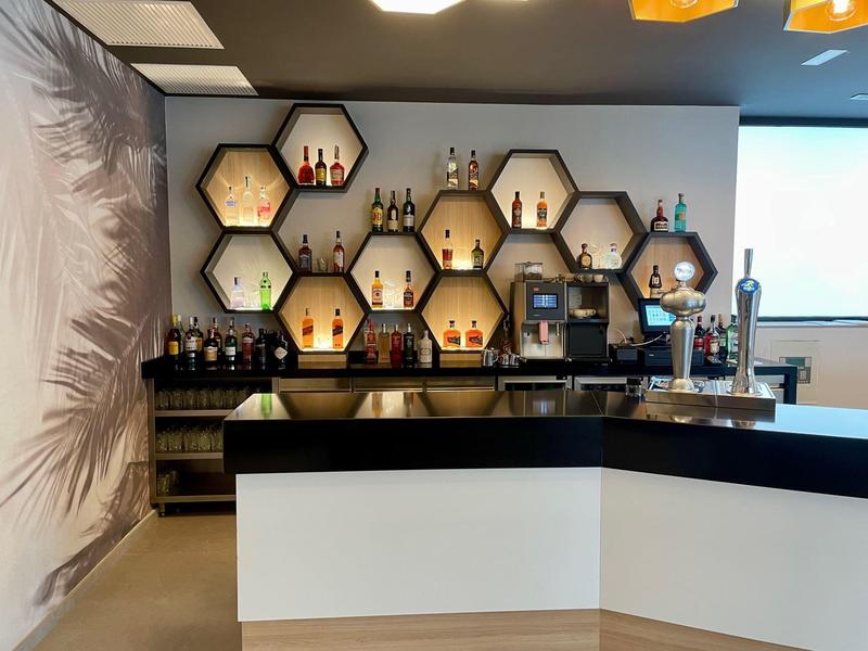 Modern bar with honeycomb shelves holding bottles and a coffee machine.
