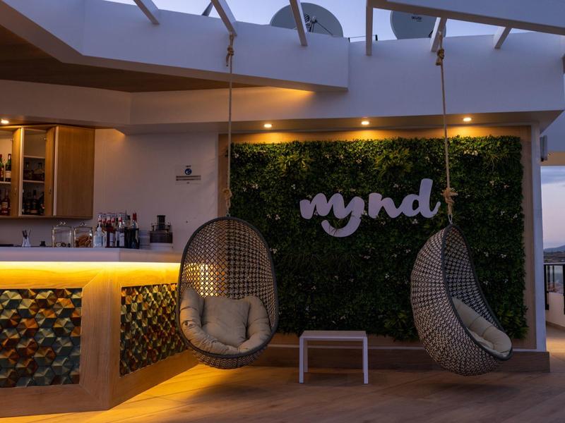 Relaxing hotel lounge with hanging egg chairs and a green wall with "mynd" logo