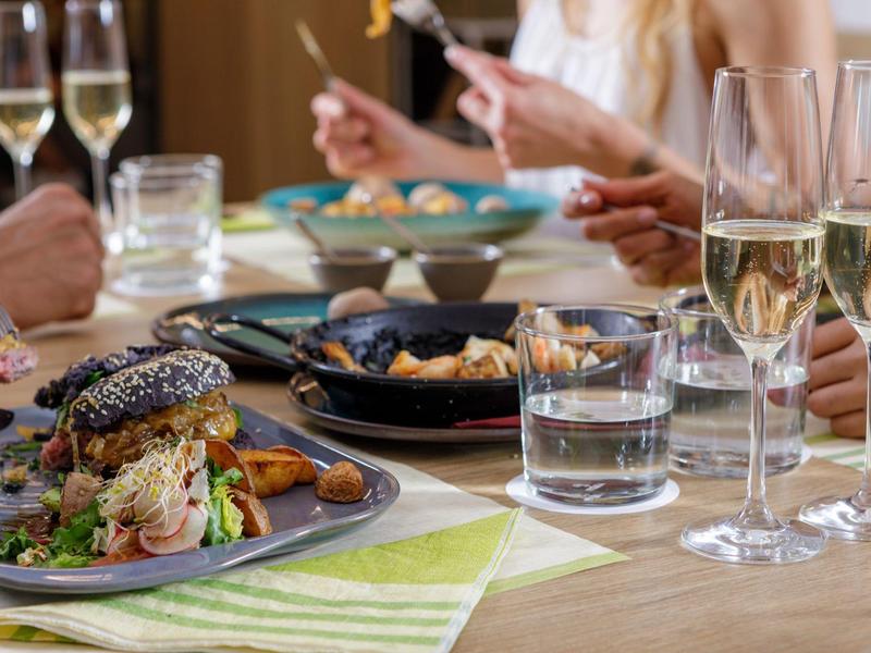 Table setting with gourmet burgers, fries, and glasses of champagne in a lively dining atmosphere.