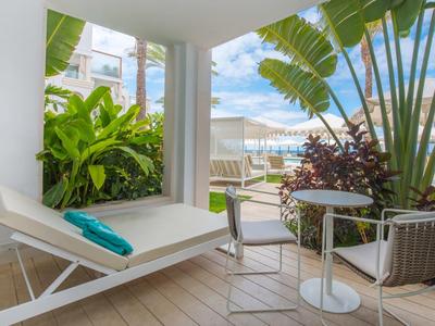 Modernes Balkon mit Sonnenliege, Pflanzen und Sitzgruppe, Blick auf Pool und Himmel.