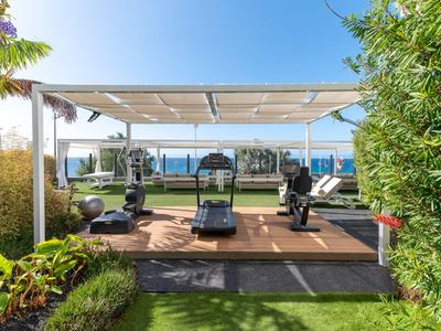 Area fitness all'aperto moderna con attrezzature e vista mare nel giardino dell'hotel.