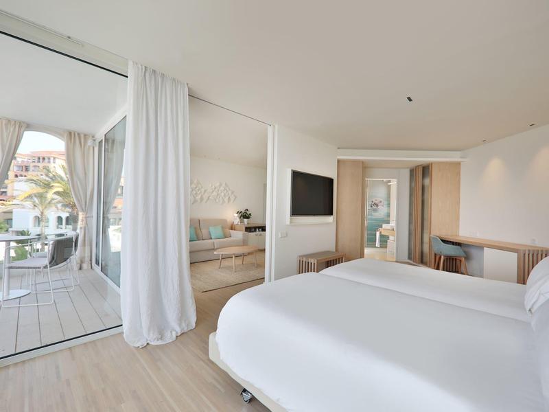 Modernes, helles Schlafzimmer mit Doppelbett, TV, Holzmöbeln und Zugang zu Terrasse mit Gartenblick.