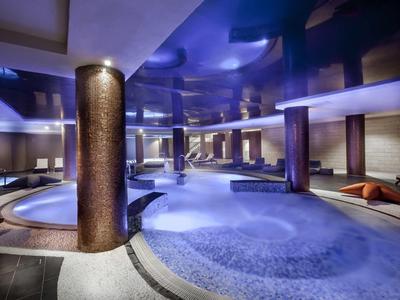 Area benessere moderna con illuminazione, piscine rotonde e zone relax.