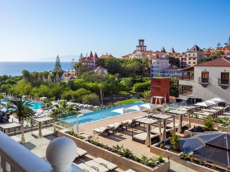 Hotel con più piscine, lettini e vista sul mare sotto un cielo soleggiato