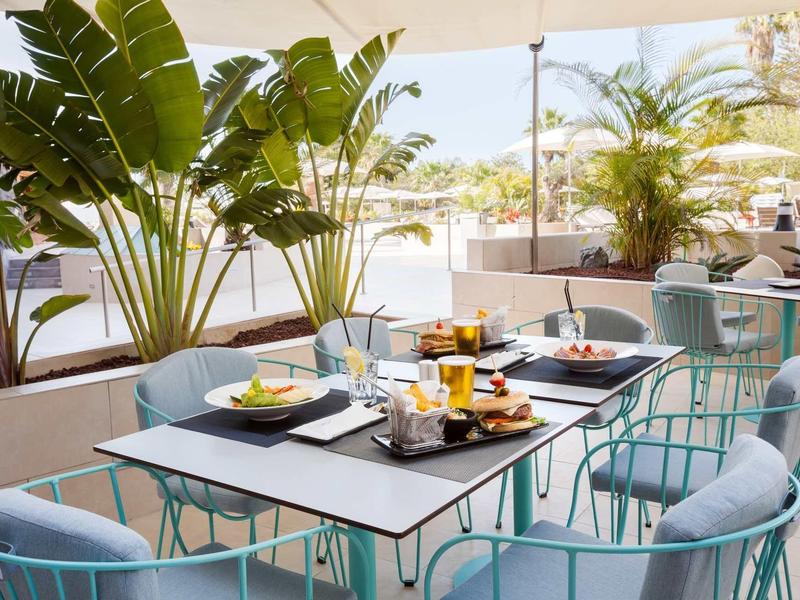 Terrazza moderna con sedie imbottite blu e tavolo apparecchiato per la colazione.