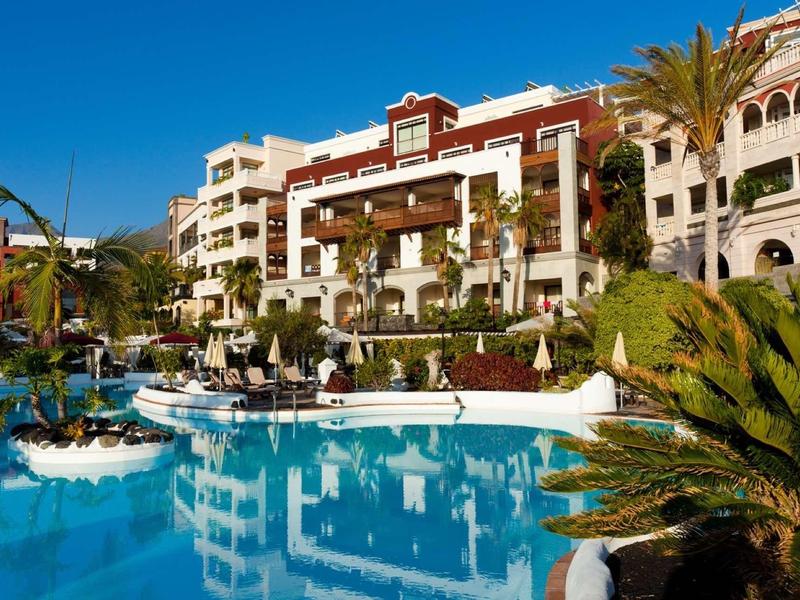 Hotel luminoso con piscina e palme sotto un cielo azzurro