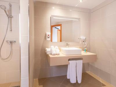 Modern hotel bathroom with sink, mirror, and towels.