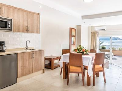 Bright dining area and kitchenette with view of terrace and sea in a hotel room.