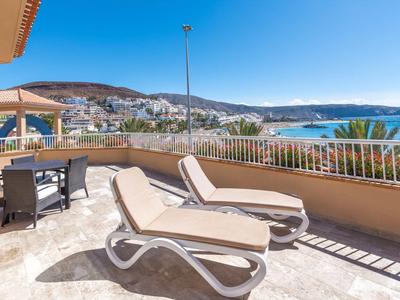 Terrazza solare con lettini e vista sul mare e sulla città sotto un cielo sereno.