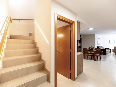 Interior con escalera, puerta de madera y área de estar y comedor abierta en tonos claros