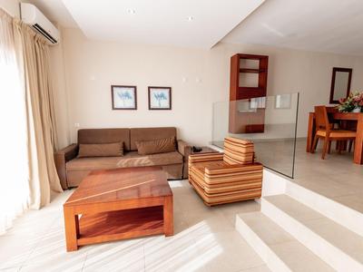 Sala luminosa con sofá marrón, mesa de centro de madera y área de comedor al fondo