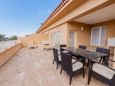 Amplia terraza con mesa de comedor y sillas de descanso bajo un cielo despejado