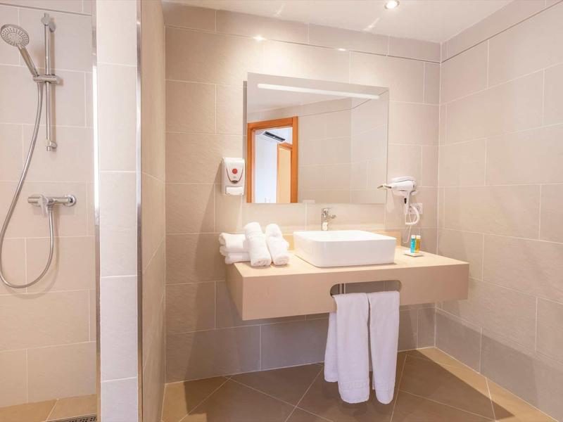 Modern hotel bathroom with sink, mirror, and towels.