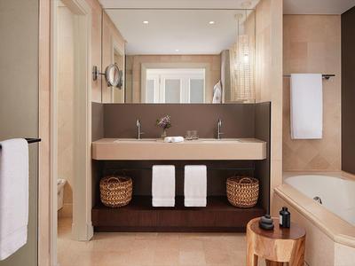 Modernes Badezimmer mit Doppelwaschbecken, großen Spiegel, Badewanne und Handtüchern in warmen Beige- und Brauntönen.