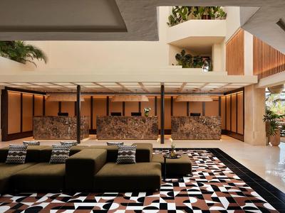 Großer, offener Raum mit modernen Sitzmöbeln, geometrischem Teppich und Wasserspiel an der Rückwand.