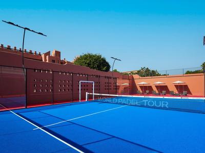 Pista de pádel azul al aire libre con cerca roja y cielo despejado