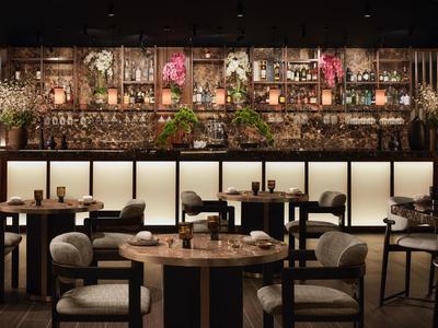 Moderne Restaurant-Innenansicht mit runden Holztischen, schwarzen Stühlen und Deckenbeleuchtung.