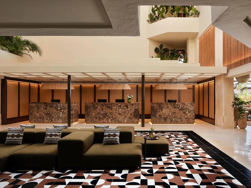 Großer, offener Raum mit modernen Sitzmöbeln, geometrischem Teppich und Wasserspiel an der Rückwand.