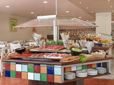 Buffet met diverse gerechten en kleurrijke tegels in een hotel-eetruimte.