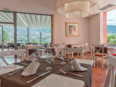 Elegant restaurant with set tables, large windows, and mountain view in the background.