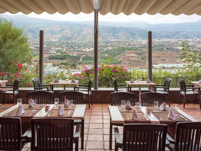 Terras van een restaurant met uitzicht op de stad en bergen op de achtergrond.