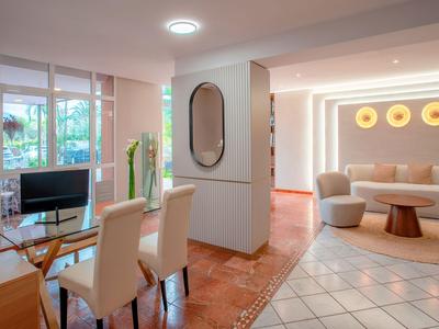 Helles Hotelzimmer mit Essbereich und gemütlicher Sitzecke in warmen Farbtönen.