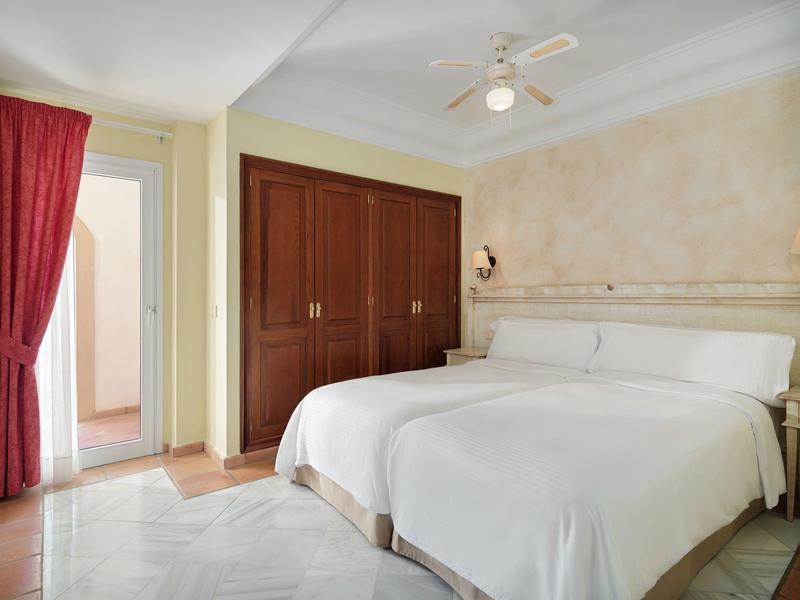 Hotelkamer met twee eenpersoonsbedden, kleine kast en toegang naar balkon of badkamer.