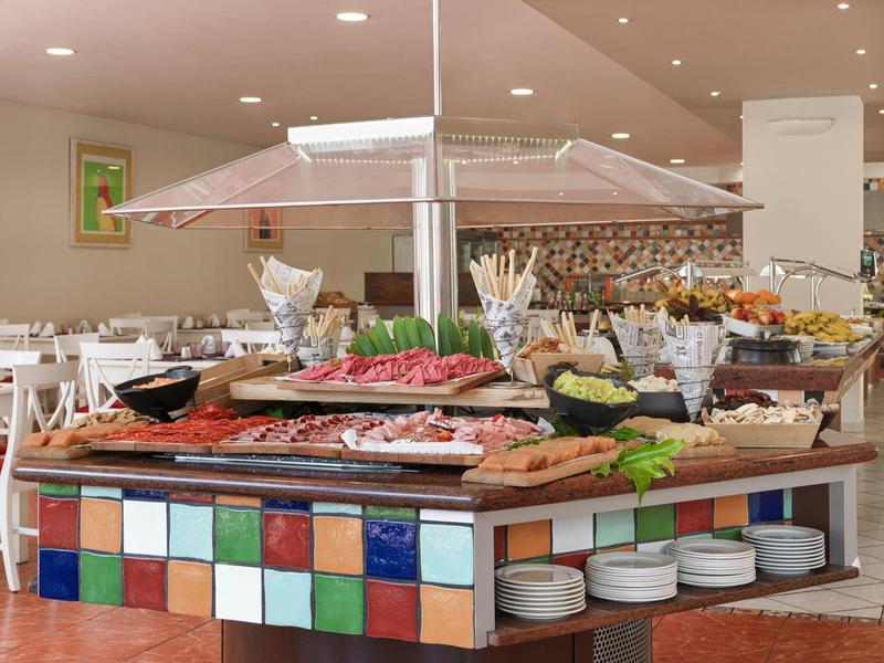 Buffet met diverse gerechten en kleurrijke tegels in een hotel-eetruimte.