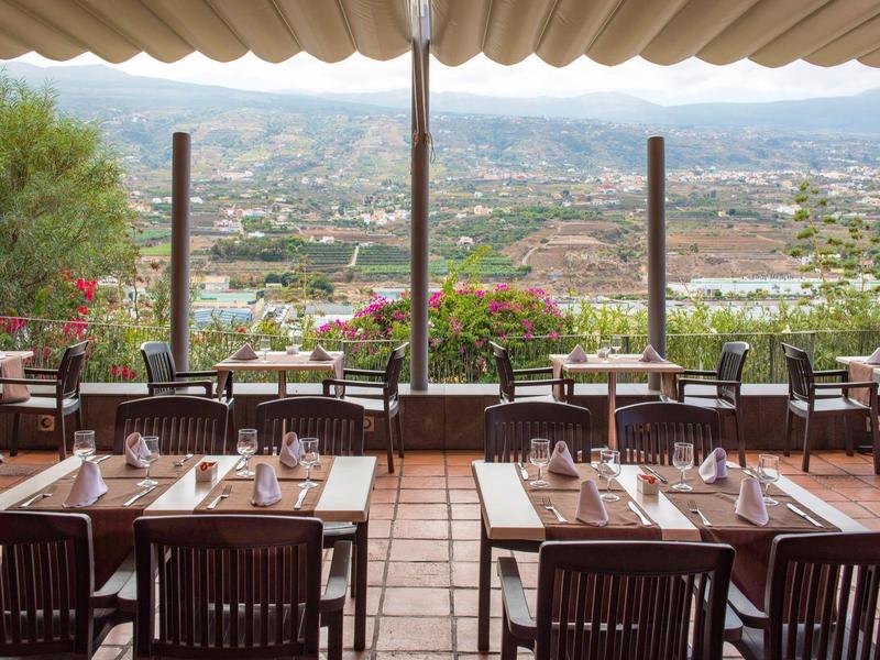 Terras van een restaurant met uitzicht op de stad en bergen op de achtergrond.