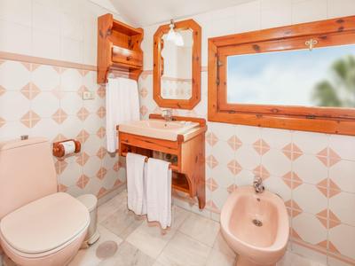 Kleines Badezimmer mit Holz-Elementen, Toiletten, Bidet, Spiegel und beige-fliederfarbenen Fliesen.