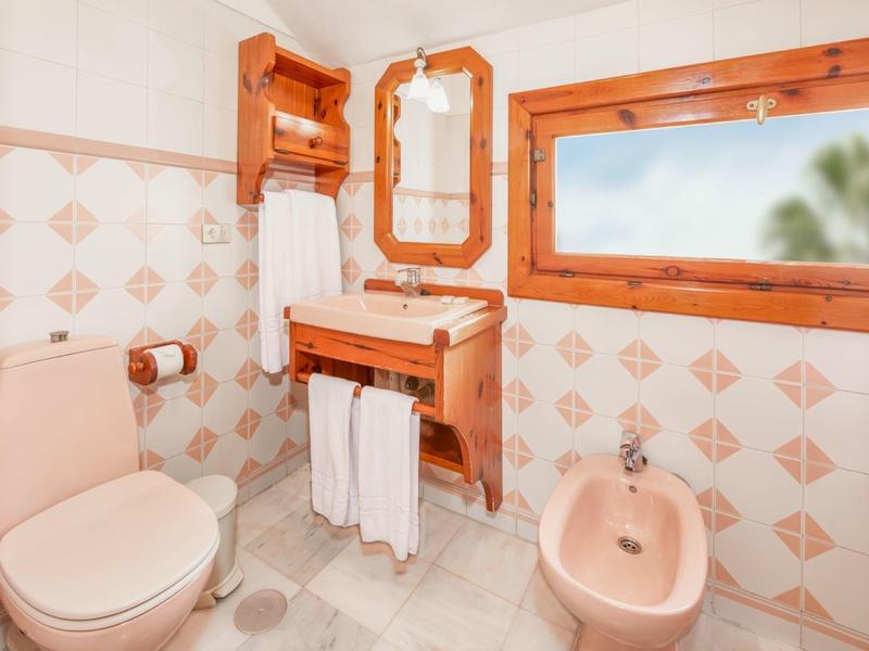 Kleines Badezimmer mit Holz-Elementen, Toiletten, Bidet, Spiegel und beige-fliederfarbenen Fliesen.