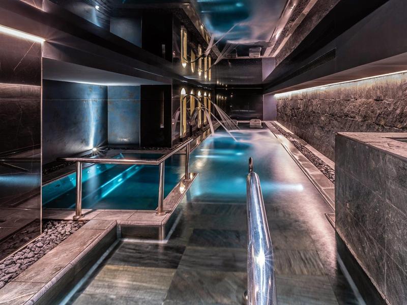 Modern indoor pool with cool lighting and concrete walls in a hotel.