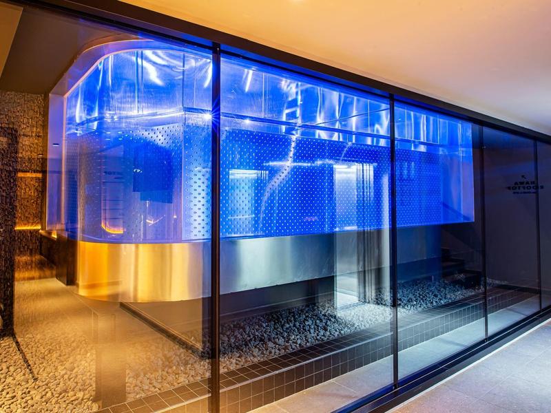 Modern room with blue-lit metallic structures behind glass.