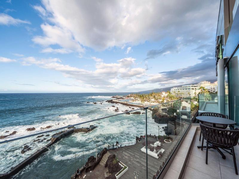 Balcony with glass railing overlooking the sea under cloudy sky